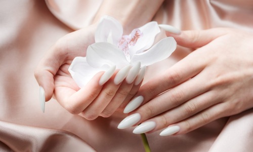 a person with white nails holding a flower
