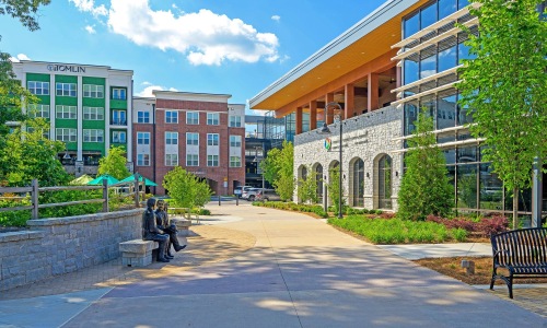 a group of buildings with a walk way benches and trees
