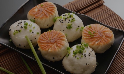 a plate of dumplings with chopsticks